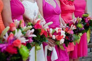 bridesmaids in colorful dresses holding bouquets at gala facility